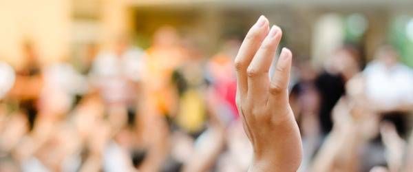 Hochgehobene Hand - Menschenmenge im Hintergrund verschwommen